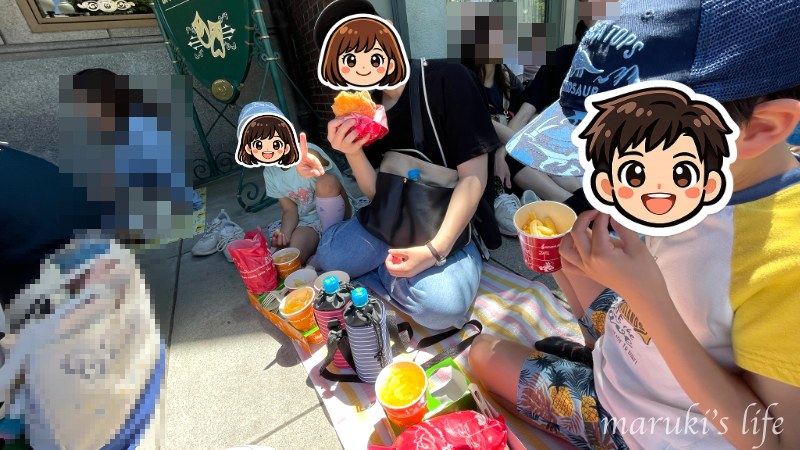 ショーの開演待ちの列でレジャーシートを敷いて食事をする様子