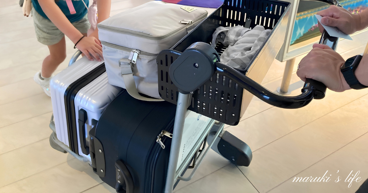 ディズニー旅行の荷物をのせたカートを家族で押している様子